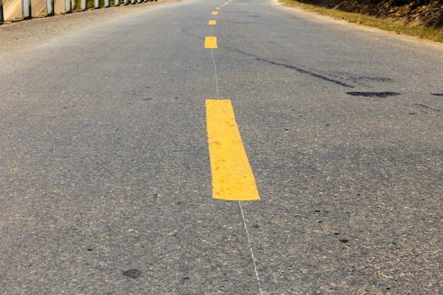 Foto gelbe unterbrochene linie auf asphaltstraße, straßenmarkierung