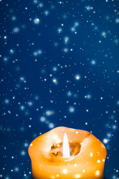 Gelbe Urlaubskerze auf blauem funkelnden schneiendem Hintergrund Luxus-Branding-Design für Weihnachten, Silvester und Valentinstag