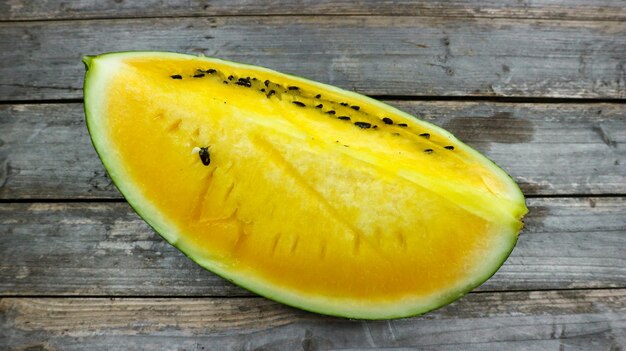 Gelbe Wassermelonenscheiben auf Holzteller und isoliert auf grauem Hintergrund. Gesunde Ernährung Antioxidans