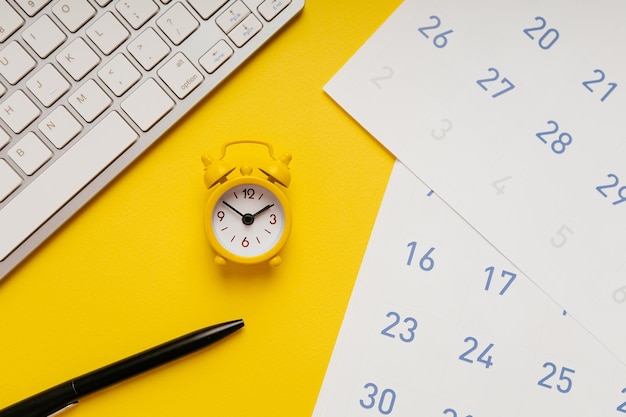 Gelbe Wecker-Tastatur und Kalender auf gelbem Hintergrund Ansicht von oben Deadline-Konzept