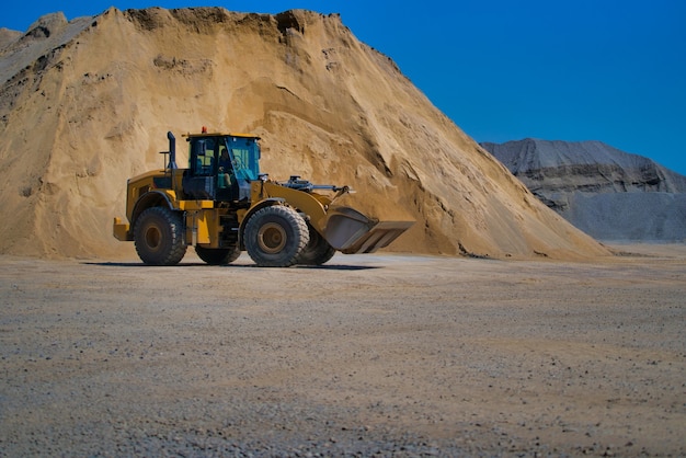 Gelber Bagger auf einer Baustelle gegen blauen Himmel.