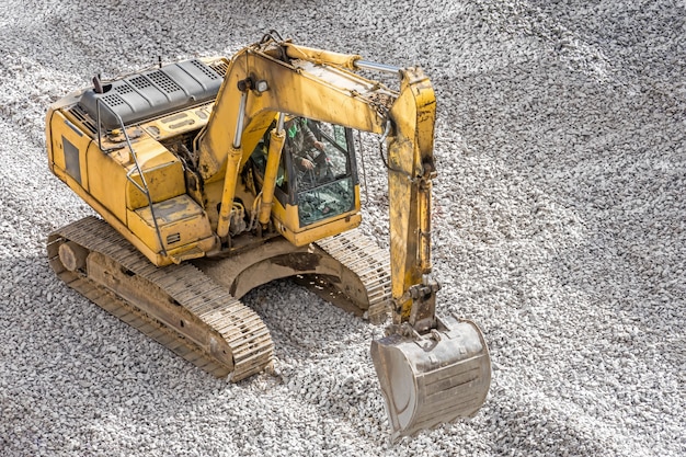 Gelber Bagger auf Schutt, der Steine auf der Baustelle nivelliert.