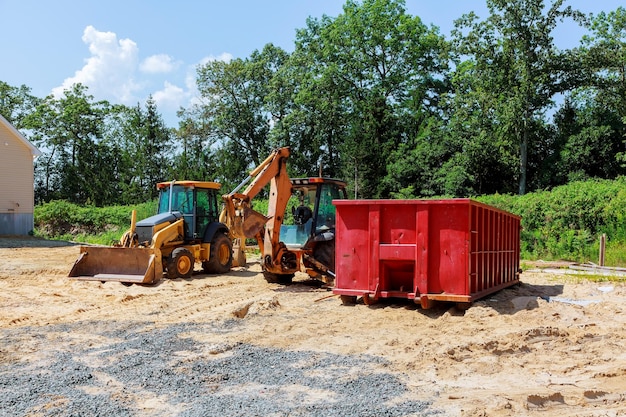 Gelber Bagger beim Bau neuer Traktorbagger und Müllcontainer