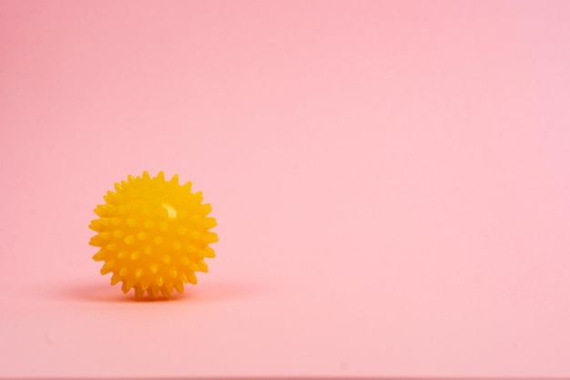 Gelber Ball einer Massagenadel auf rosafarbenem Hintergrund das Konzept der Prävention von Plattfüßen Hallux