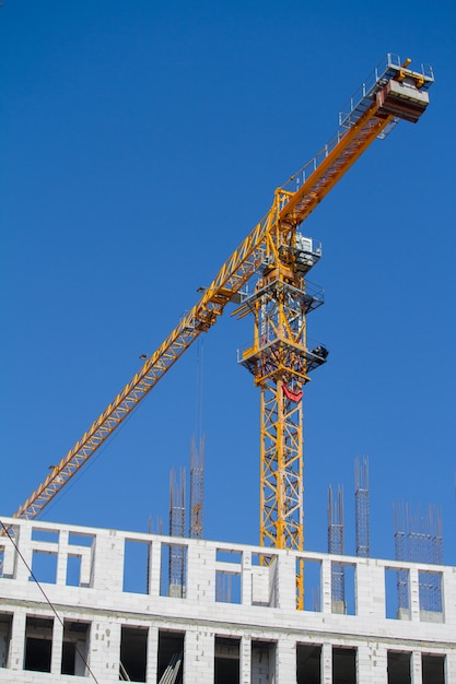 Gelber Bauturmkran nahe Neubau über blauem Himmel, selektiver Fokus