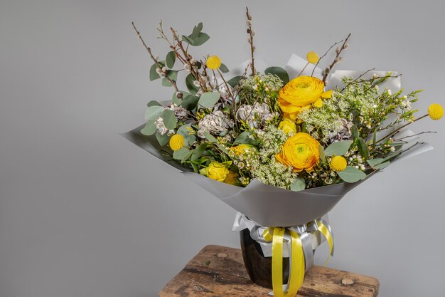 Gelber Blumenstrauß der gelben und orange Blumen auf grauem grauem Hintergrund