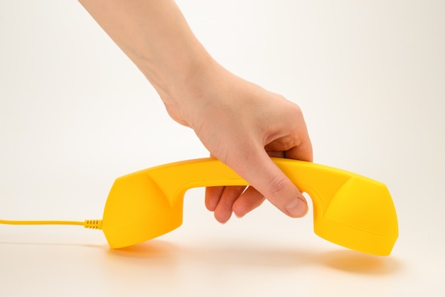 Gelber Handapparat in der Frauenhand lokalisiert auf Weiß.