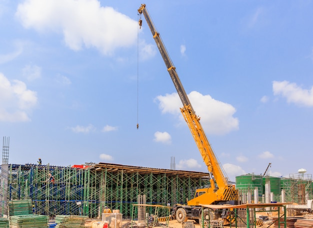 Gelber hydraulischer LKW-Kran, der im Bau auf einer Baustelle steht.