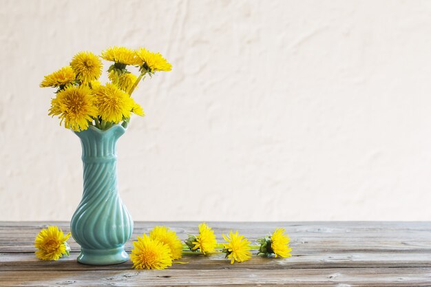 Gelber Löwenzahn in blauer Vase auf weißem Hintergrund