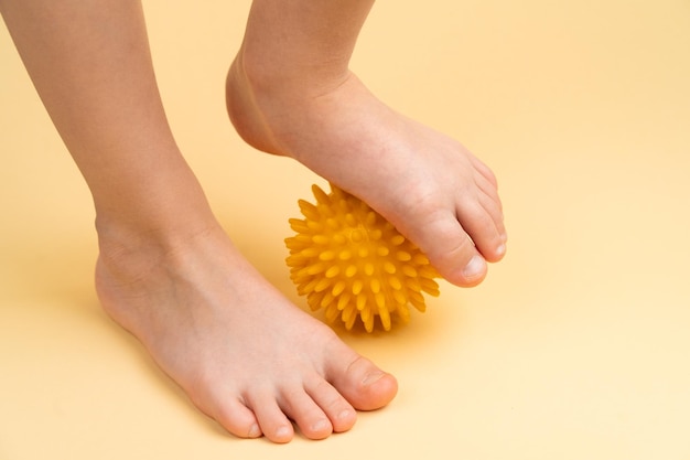 Foto gelber nadelball für massage und physiotherapie auf beigem hintergrund mit dem bild eines kinderfußes, dem konzept der prävention und behandlung von hallux valgus