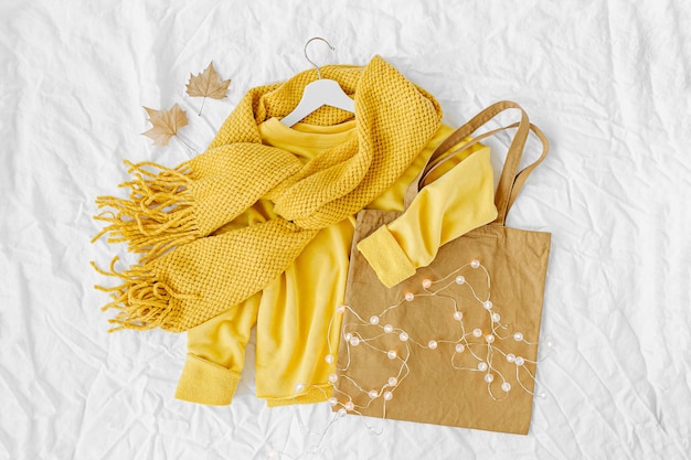 Gelber Pullover mit Strickschal und Tragetasche. Herbstmode kleidet Collage auf weißem Hintergrund. Draufsicht flach.