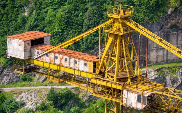 Gelber Riesenbaukran auf den Berghügeln. Am Kran zeigen sich Rostspuren