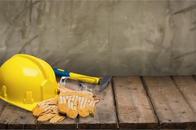 Gelber schutzhelm und arbeitshandschuhe aus leder, hammer