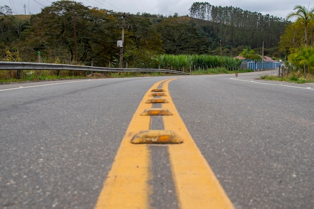 Gelber Streifen, der die rollenden Fahrspuren einer Straße in einer ländlichen Gegend mit dem Berg im Hintergrund teilt.