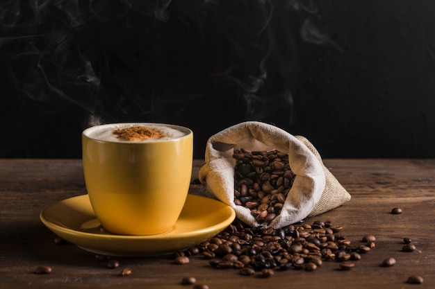 Gelber Tasse Kaffee und Sack mit Bohnen