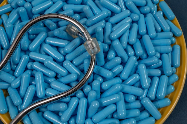Foto gelber teller voller blauer medikamentenkapseln, die eine überdosis drogen darstellen