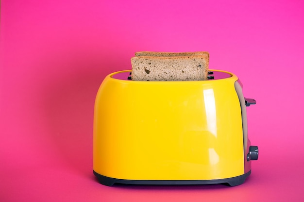 Gelber Toaster auf einem rosa Hintergrund