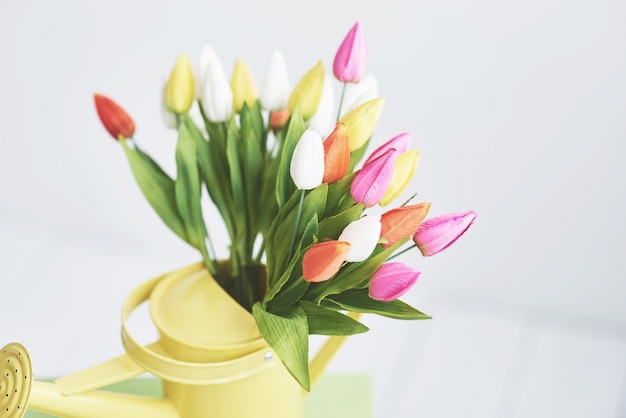 Gelber Trichter mit kleinen farbigen Blumentulpen. Schöne Frühlingsblumen