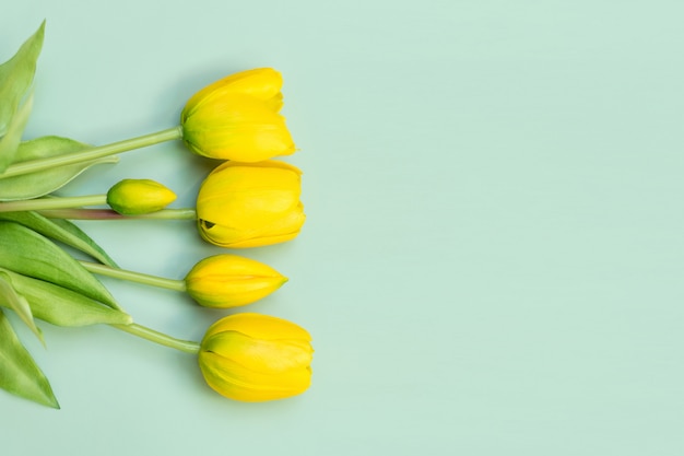 Gelber Tulpenblumenstrauß auf grünem Tisch. Flache Lage, Draufsicht. Minimales Blumenkonzept. Frühlingsblumen