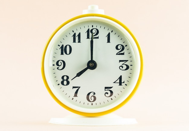 Gelber Wecker zeigt die Zeit 20 Uhr auf einem hellen Hintergrund an