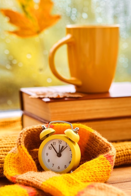 Foto gelber weckerbecher auf büchern in der nähe des fensters es regnet