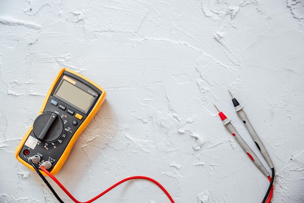 Gelbes Digitalmultimeter mit Sonden auf weißem Hintergrund mit freiem Kopierplatz