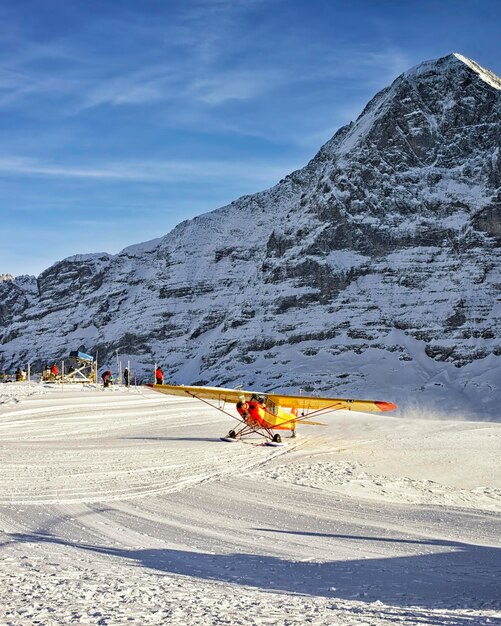 Gelbes Flugzeug, das im Winter zum alpinen Ferienort in den Schweizer Alpen landet