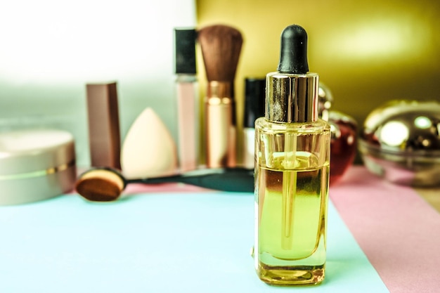 Gelbes, goldenes, transparentes Glasglas mit Primer-Öl-Make-up-Basis auf dem Hintergrund eines Make-ups