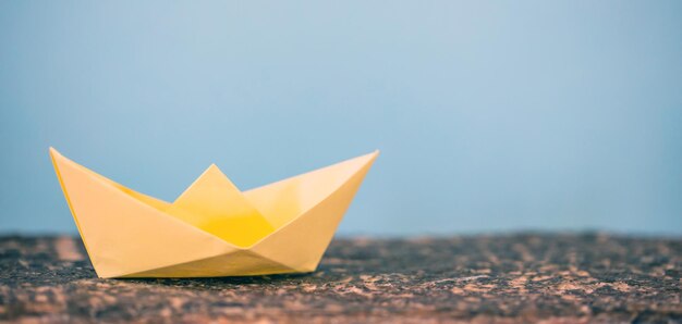 Foto gelbes papier gefaltetes origami-boot auf blauem hintergrund