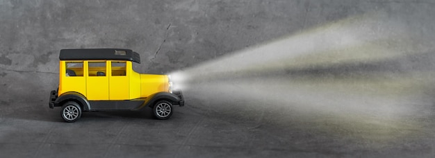 Gelbes Spielzeug-Retro-Auto auf grauem Hintergrund. Trendfarben 2021. Platz für Text.