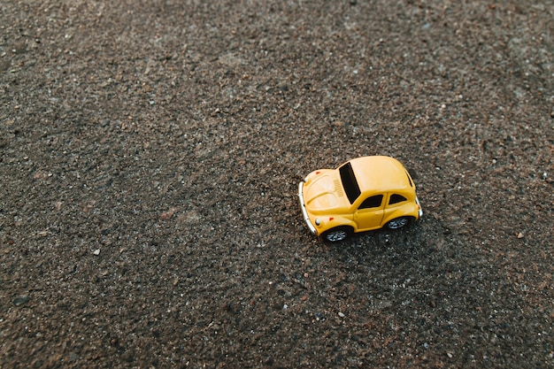 Gelbes Spielzeugauto auf dem Strand im Sonnenlicht im Sommer.