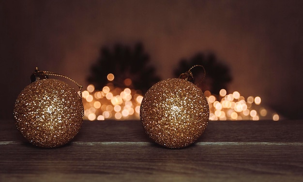 Gelbgoldkugeln Weihnachtsspielzeug auf dem Hintergrund einer leuchtenden Girlande mit Weihnachten