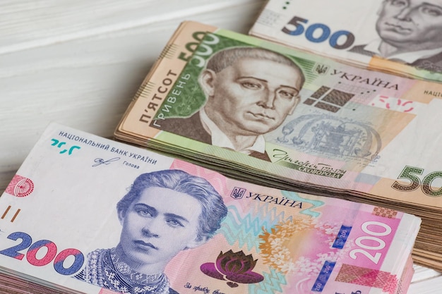 Geld der Ukraine. Stapel ukrainischer Griwna-Banknoten in den Händen auf weißem Holztisch. Griwna 200 und 500