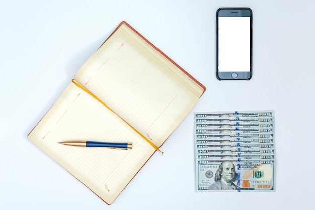 Geld ein Smartphone und ein Notizbuch mit dem Stift lokalisiert