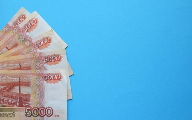 Geld von Russland. Banknoten und Münzen auf blauem Hintergrund. Nahaufnahme der russischen Rubel verschiedener Konfessionen. Finanzkonzept. Platz kopieren