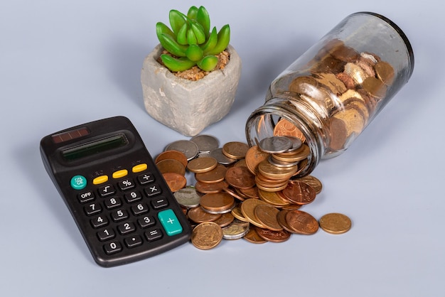 Geldfinanzgeschäftswachstumskonzeptmünzen im Glasgefäß mit Taschenrechner