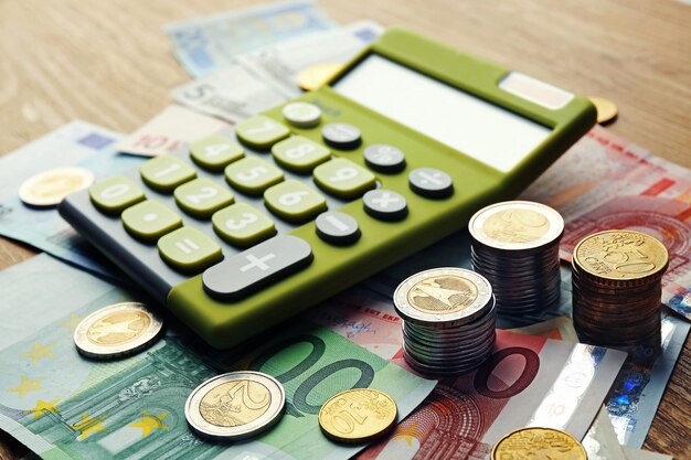 Foto geldkonzept grüner taschenrechner mit banknoten und münzen auf holztisch