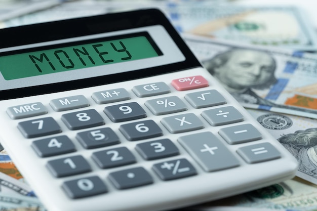 Geldtext auf dem taschenrechner auf us-dollar-hintergrund business investment income accounting und auditing money concept
