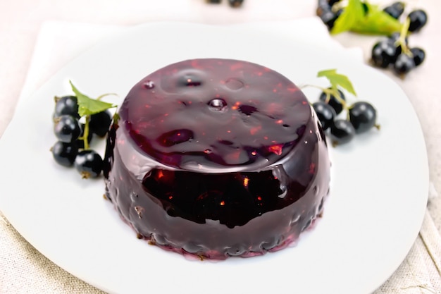 Gelee aus einer schwarzen Johannisbeere mit Beeren in einem Teller auf einem Handtuch auf dem Hintergrund eines Steintisches