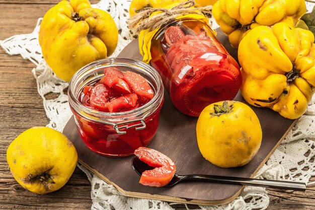 Geléia caseira de marmelo em uma jarra de vidro. Frutas frescas, geleia doce, arranjo vintage. Antigo fundo de madeira, close-up