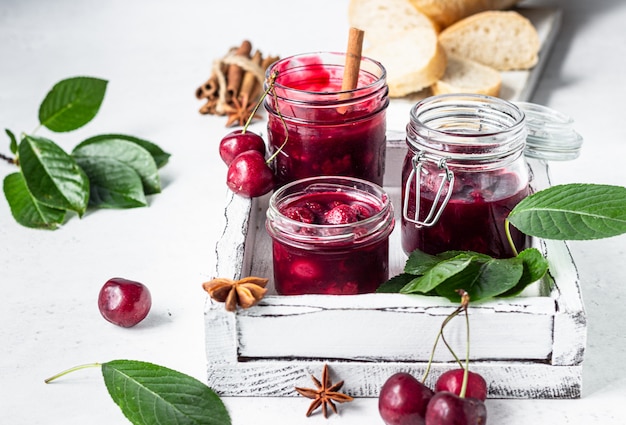 Geléia de cereja com especiarias (canela, anis) com cerejas frescas nos potes e pão.