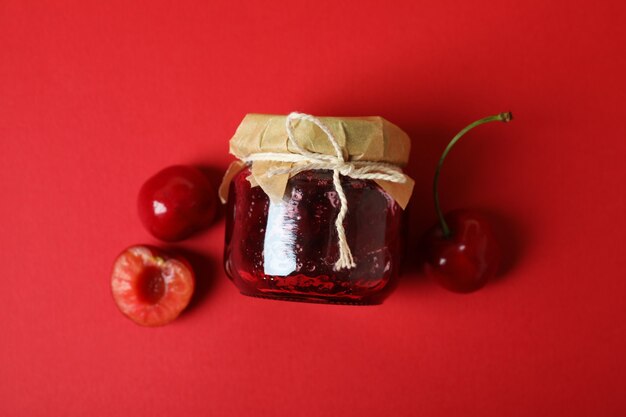 Foto geléia de cereja e ingredientes em fundo vermelho