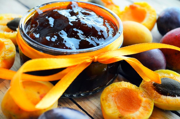 Foto geléia de damasco e ameixa e frutas frescas na mesa de madeira