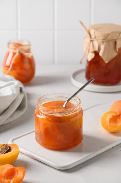 Geléia de damasco em frasco de vidro com frutas da colheita do verão e comida enlatada