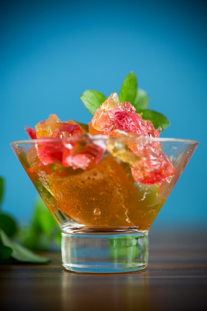 geléia de fruta doce colorida em um copo de vidro em uma mesa de madeira