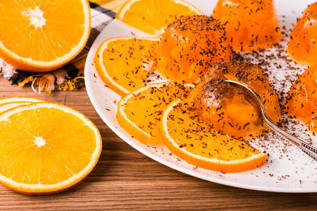 Foto geléia de laranja com lascas de chocolate, uma colher e fatias de laranjas