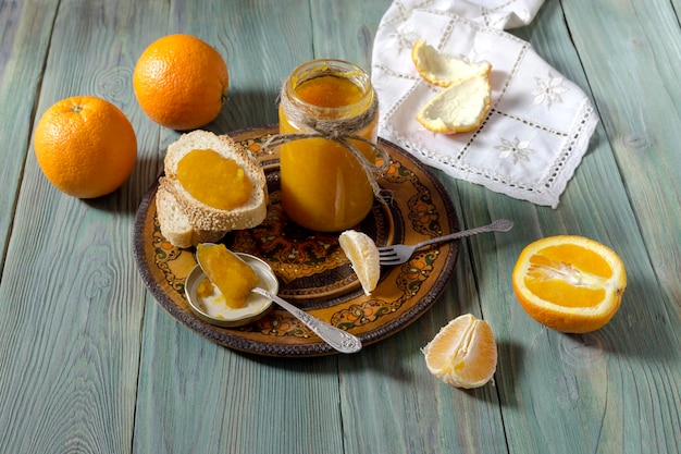 Geléia de laranja em uma jarra laranjas e biscoitos em uma mesa de madeira fechada