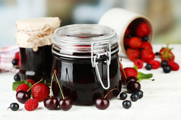 Geléia saborosa com frutas em potes de vidro na mesa de madeira