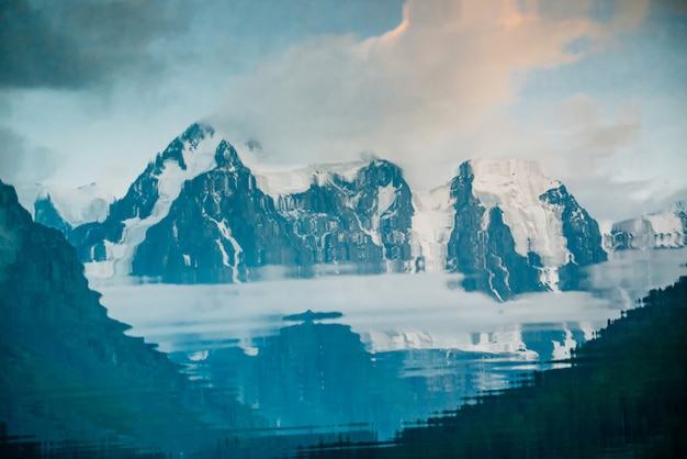 Geleira enorme refletida na superfície da água. Molhe a reflexão de montanhas rochosas nevado gigantes sob o céu nebuloso. Névoa espessa nas montanhas. Paisagem atmosférica. Reflexão tranquila no lago da montanha.