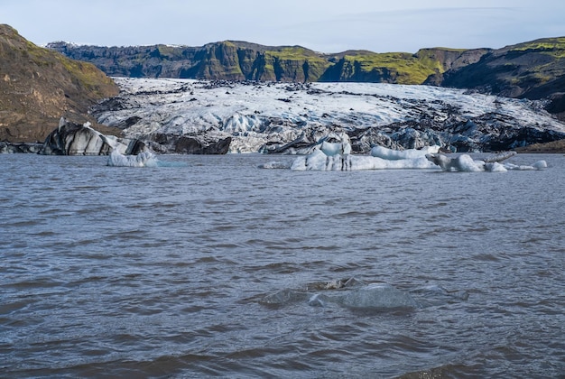 Geleira solheimajokull no sul da islândia a língua desta geleira desliza do vulcão katla bela lagoa glacial com blocos de gelo e montanhas ao redor pessoas irreconhecíveis